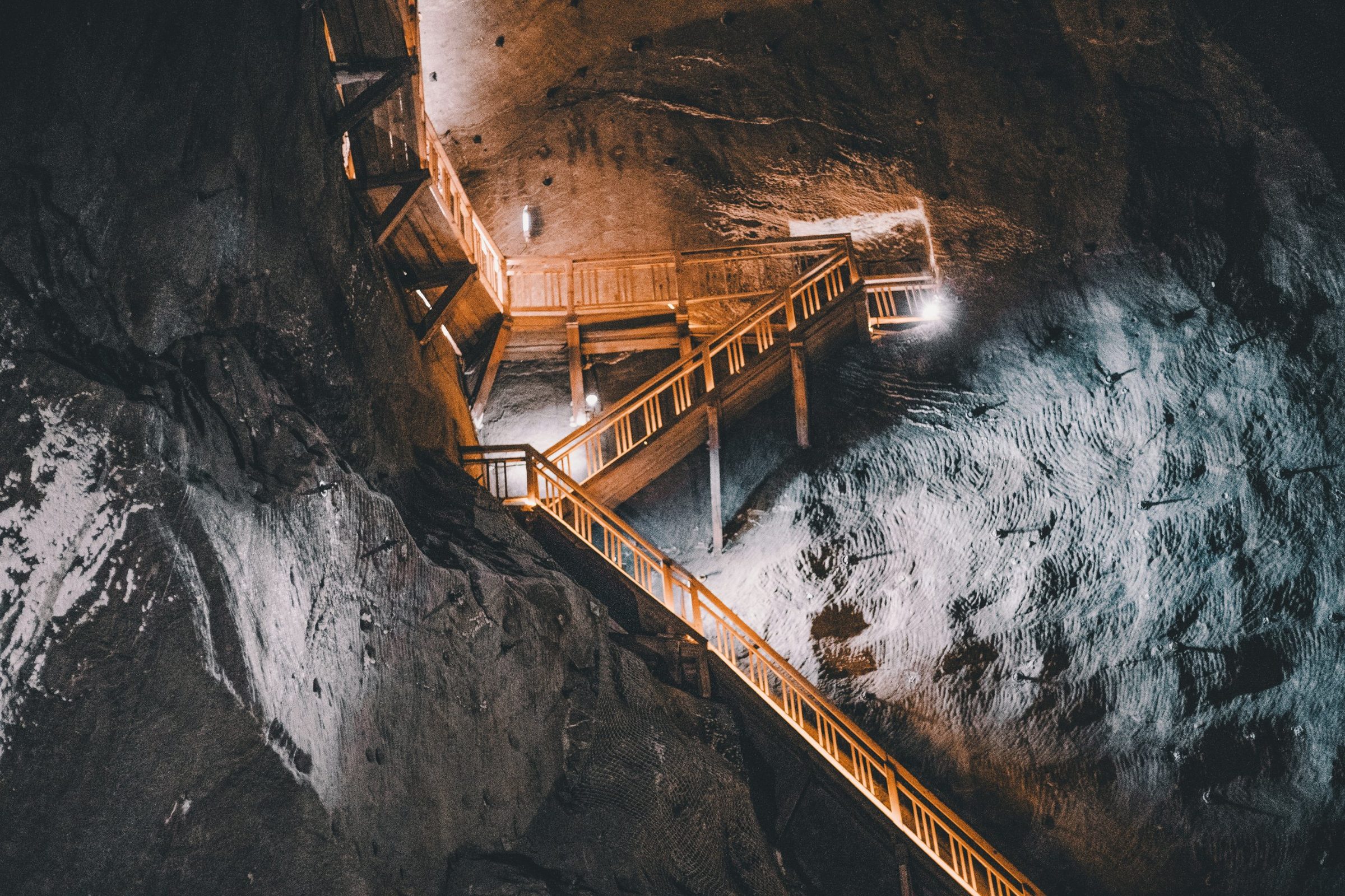 Timber stairways descending through a lit underground mine chamber