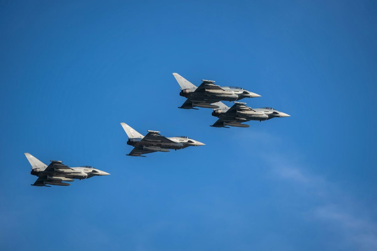 Four Eurofighter Typhoon jets flying in formation against a blue sky